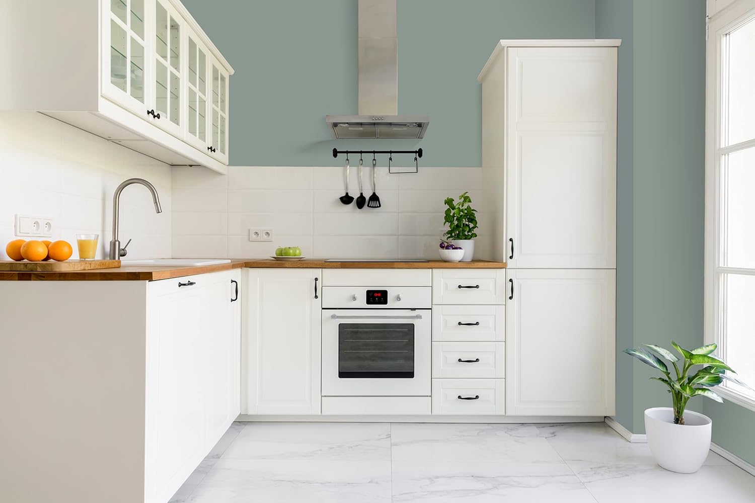 Modern kitchen with white cabinets finished in thick satin finish paint, wooden countertops, built-in oven, and stainless steel range hood. A plant and utensils are on the counter as sunlight enters through a window. A potted plant sits on the floor.