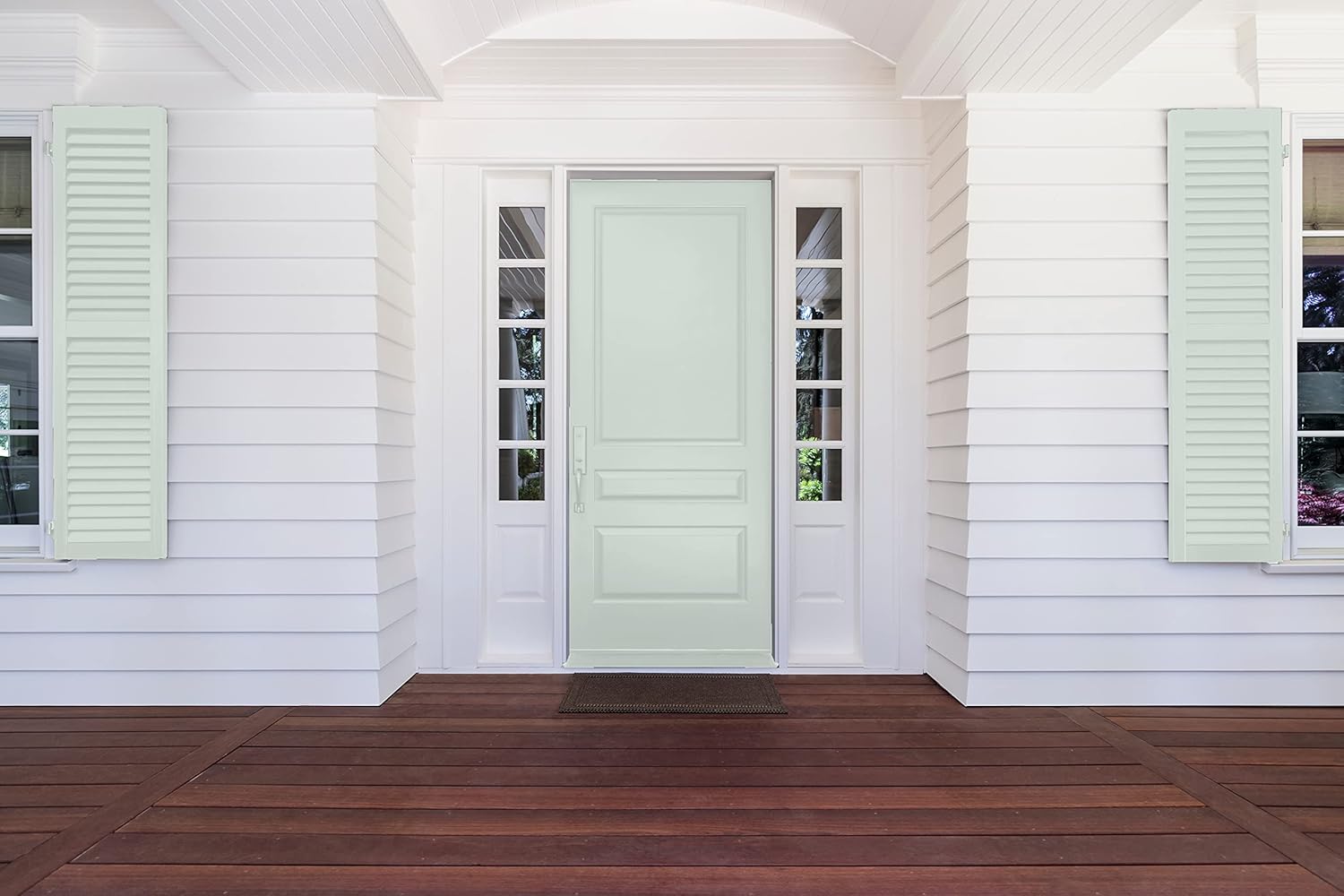 A pale mint green front door painted with premium paint and glass panels on either side is set in a white-paneled house with light green shutters and a dark wooden porch floor.
