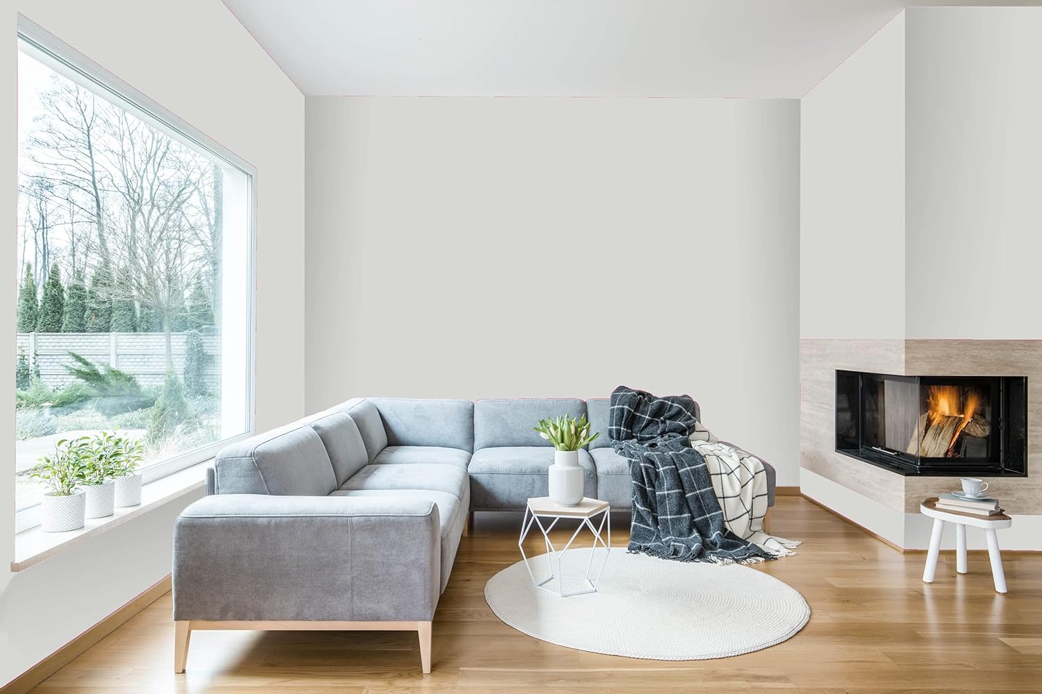 A bright, modern kitchen featuring white cabinets, a wooden countertop, and a stainless steel oven. A potted plant and a bowl of oranges add a touch of greenery and color to the space. The room has large windows, allowing natural light to fill the area.