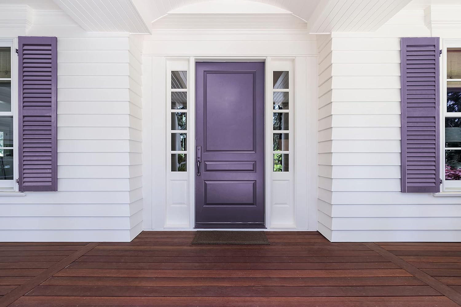 A front entrance of a house with a purple door, flanked by narrow windows and purple shutters painted in thick satin finish paint, surrounded by white siding and a wooden porch floor.