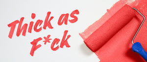 A red paint roller applies thick red paint with a satin finish on a white surface, next to handwritten text in red that says Thick as F*ck. Perfect for those wanting paint and primer in one from an Amazon paint brand.